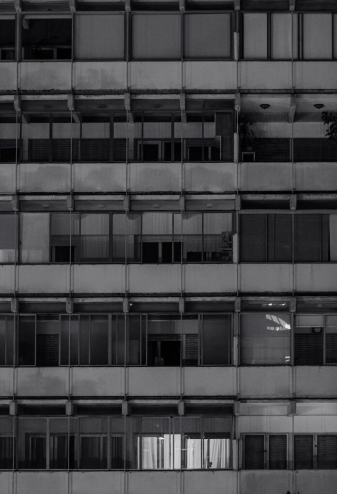 Black and white facade of an urban apartment building with numerous windows.